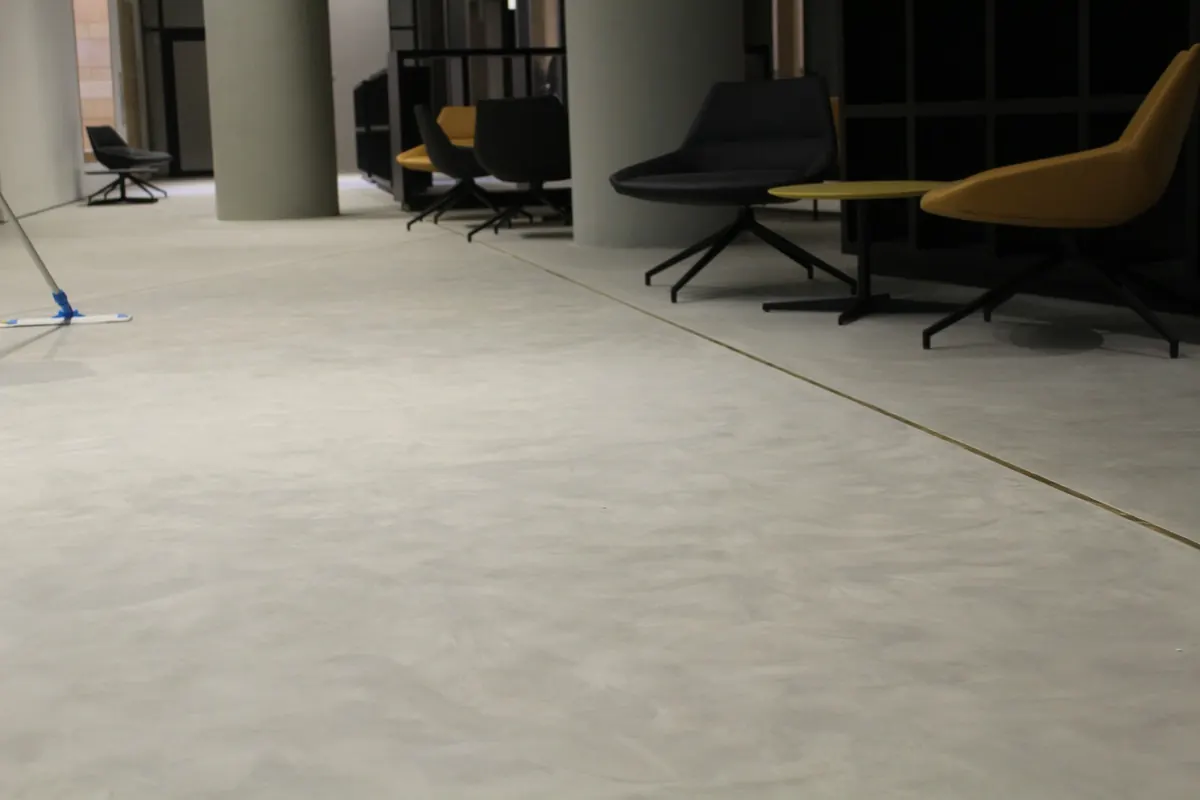 A freshly mopped lounge floor with armchairs and a mop at the edge